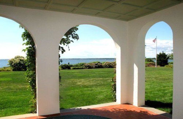 A view of a lush green field from a porch with arches