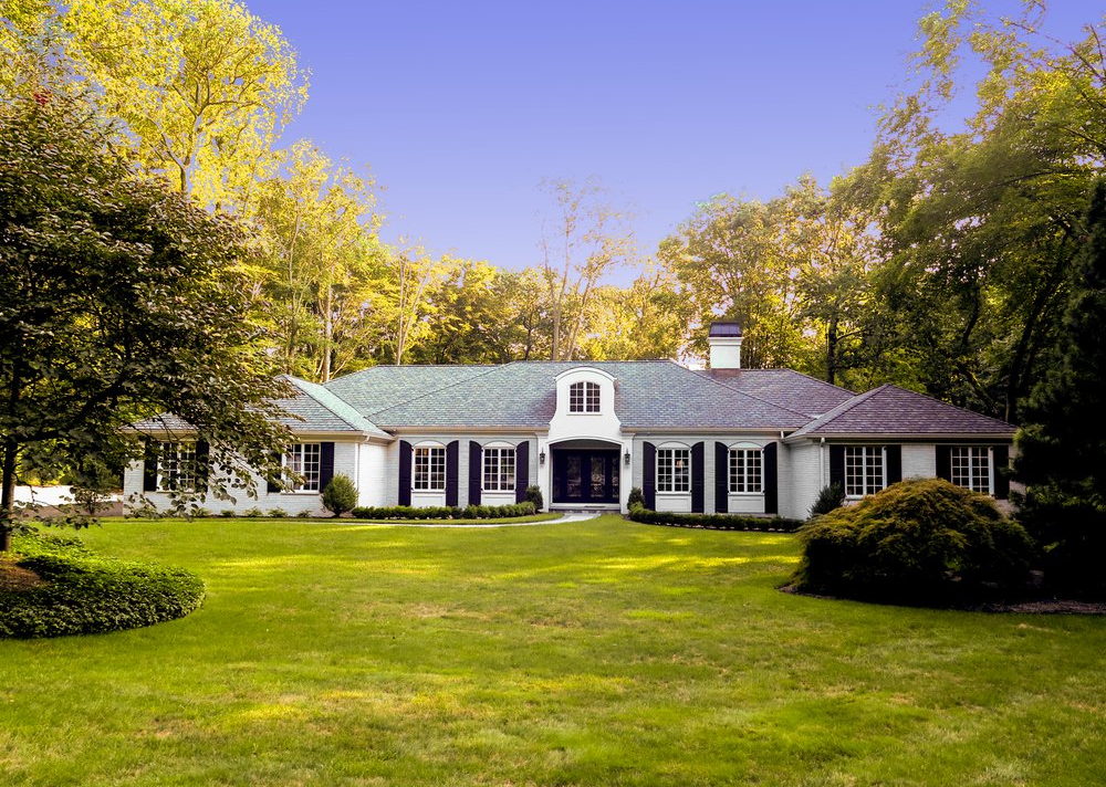 A large white house with a blue roof and black shutters