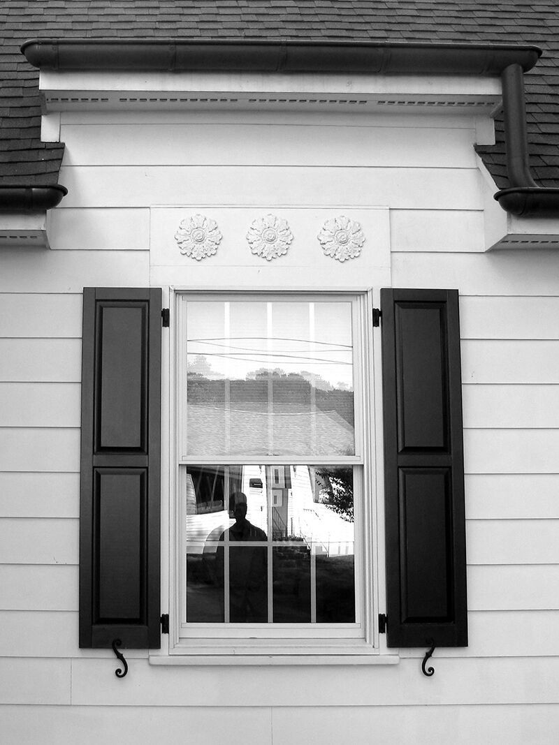 A black and white photo of a window with black shutters