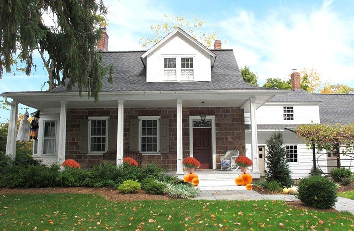 A large house with a porch and pumpkins in front of it