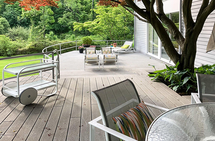 There is a table and chairs on the deck of a house.