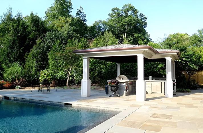 A gazebo with a grill and a swimming pool in the background