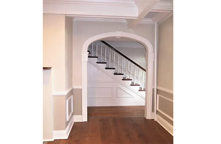A hallway leading to a staircase with a wooden railing