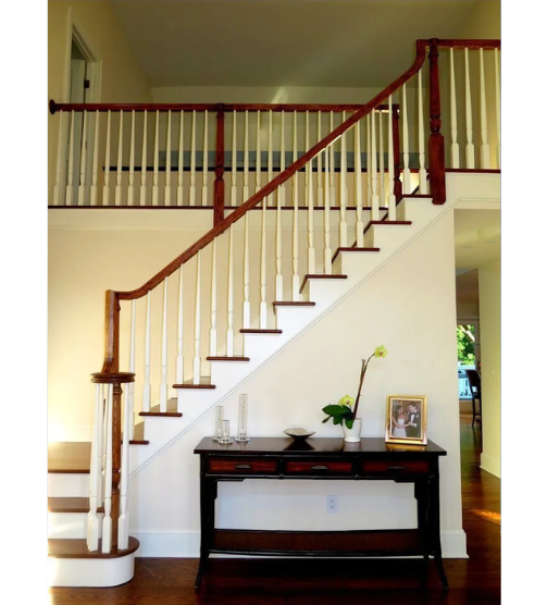 A staircase with a wooden railing and a table underneath it