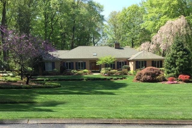 A large house with a lush green lawn and trees in the background.