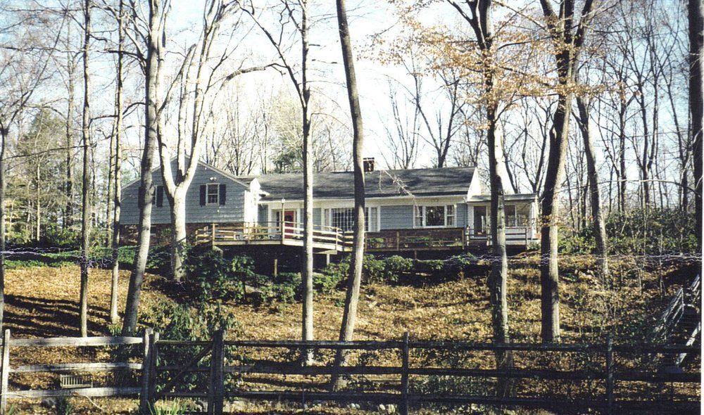 A house is surrounded by trees and a fence