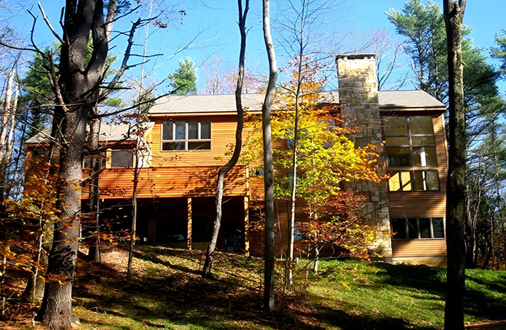 A large house is surrounded by trees on a hillside