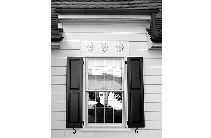 A black and white photo of a window with black shutters