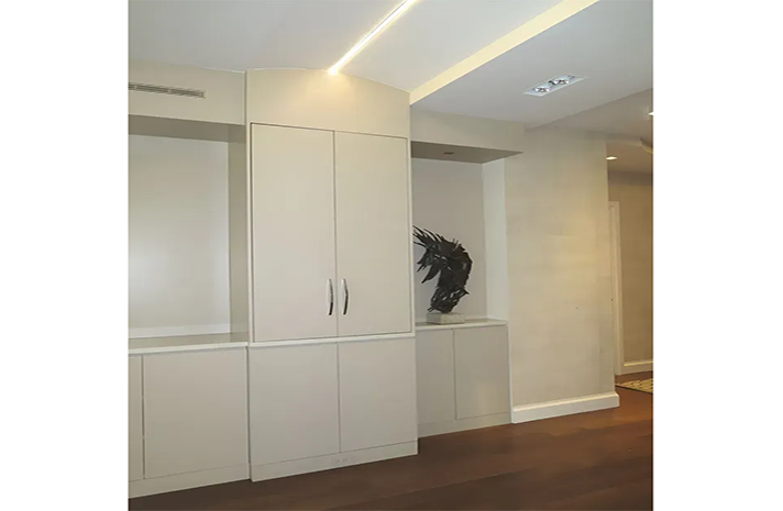 A hallway with white cabinets and a statue on the wall.