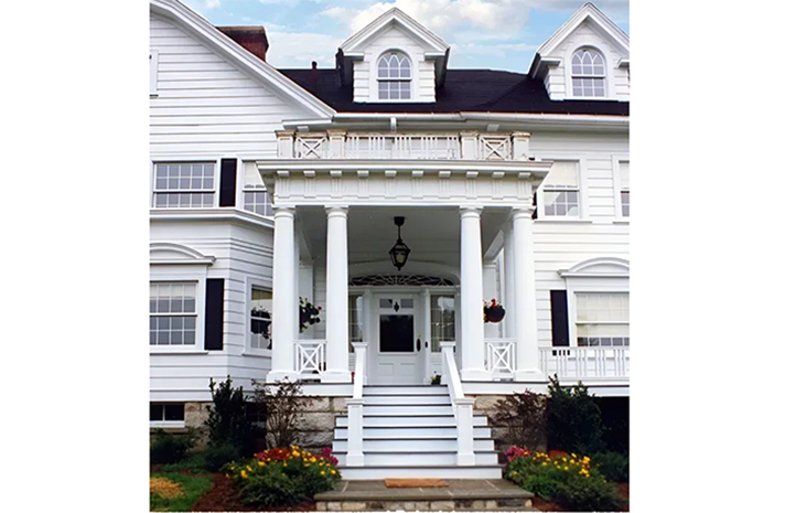 A large white house with a porch and stairs