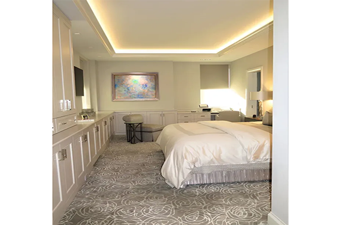 A bedroom with a large bed and a painting on the wall.