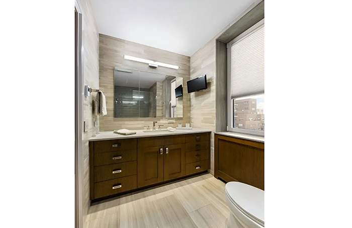 A bathroom with a sink , toilet , mirror and window.