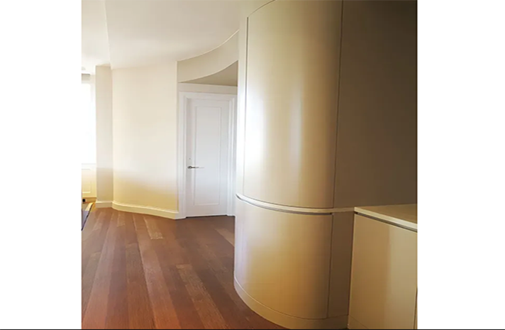 A hallway with a curved wall and a wooden floor