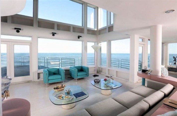 A living room with a couch and chairs and a view of the ocean