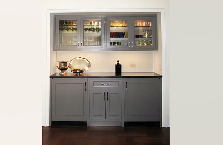 A kitchen with gray cabinets and black counter tops