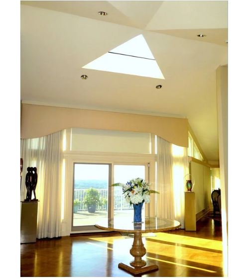 A room with a skylight and a vase of flowers on a table