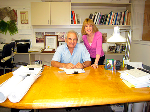 A man and a woman are sitting at a desk in an office