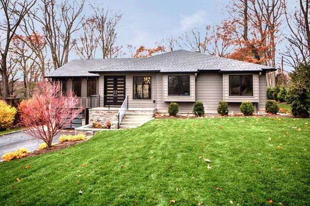 A house with a lush green lawn and trees in the background.