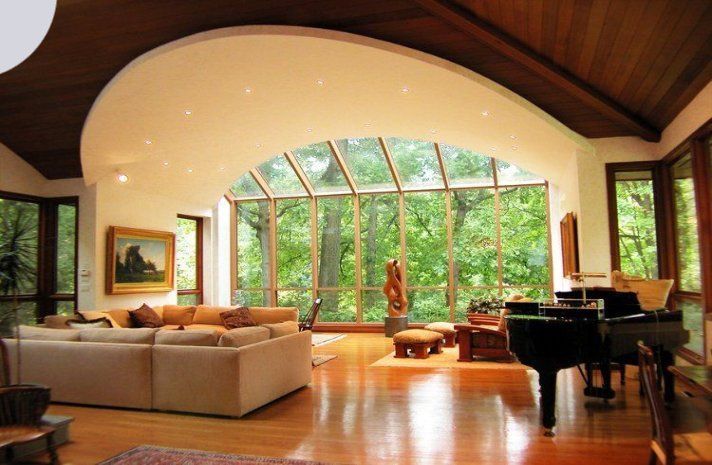 A living room with a piano and lots of windows