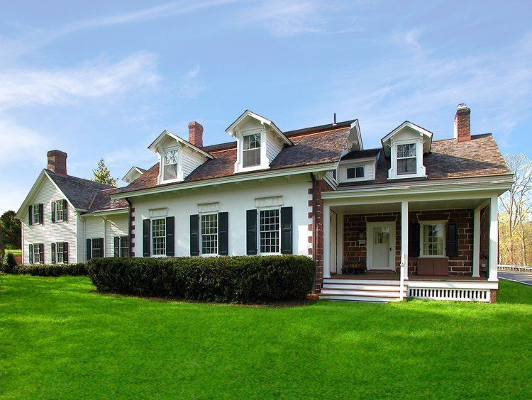 A large white house with black shutters and a large porch