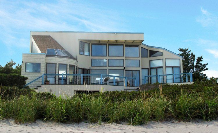 A large house sits on top of a sandy hill