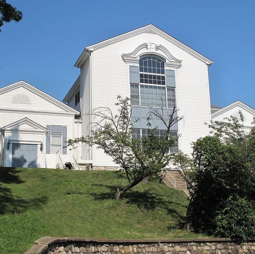 A large white building sits on top of a grassy hill