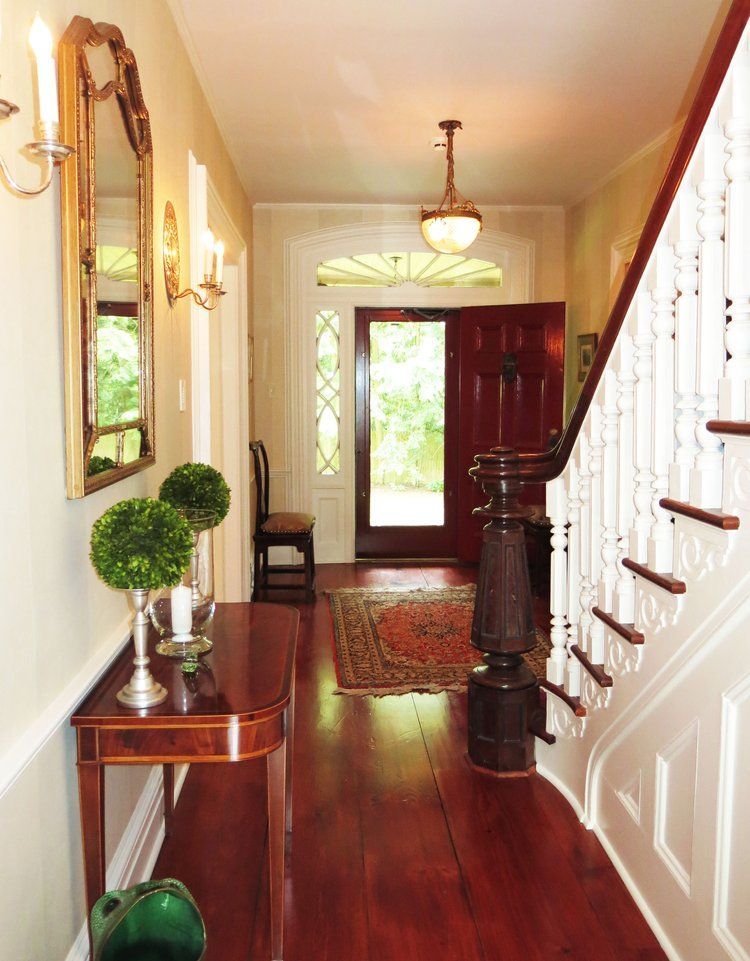 A hallway with stairs and a table in the middle