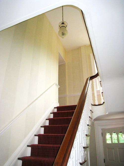 A staircase with a red carpet and a white railing