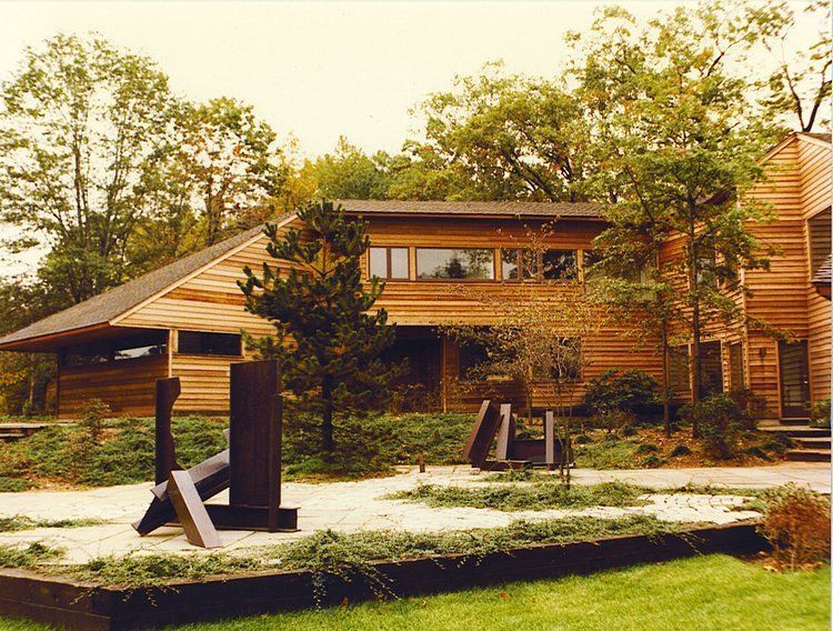 A large wooden house with a sculpture in front of it