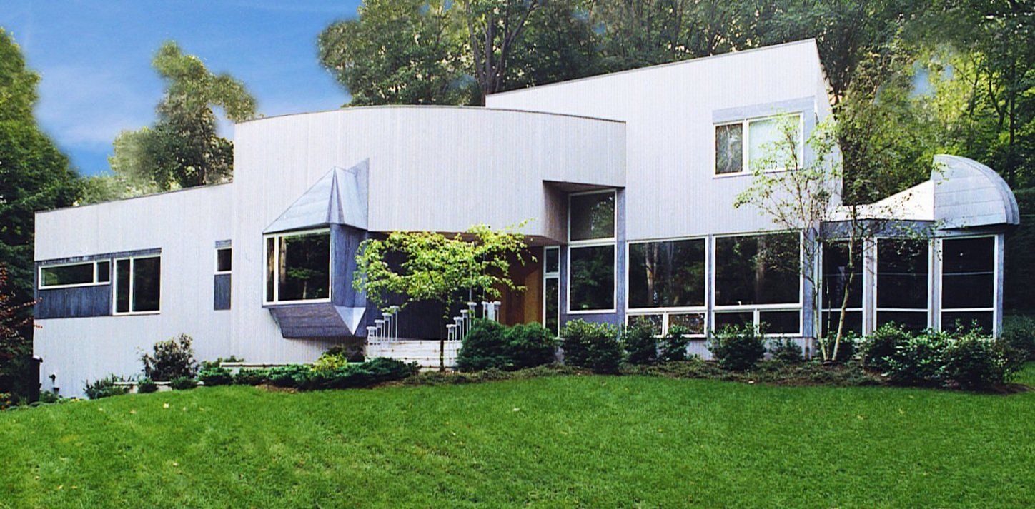 A large white house sits in the middle of a lush green field
