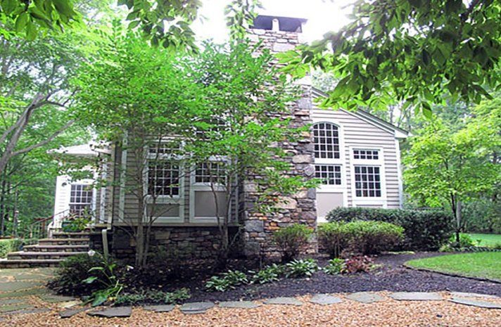 A house with a stone chimney is surrounded by trees