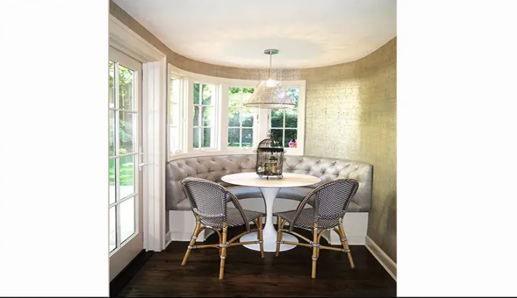 A dining room with a table and chairs in front of a window.