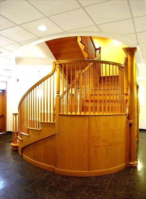 A wooden spiral staircase with a metal railing