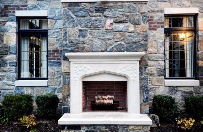 There is a fireplace in front of a stone building.