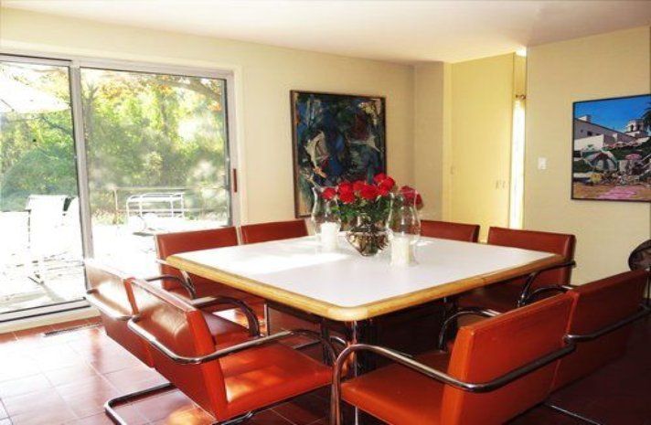 A dining room with a table and chairs and a painting on the wall
