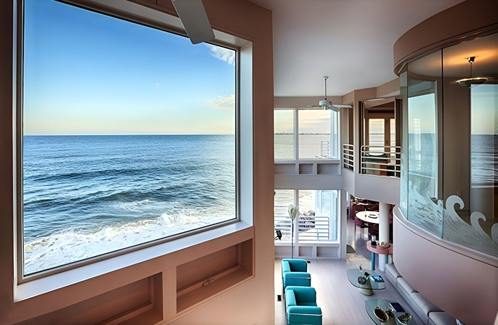 A living room with a large window overlooking the ocean
