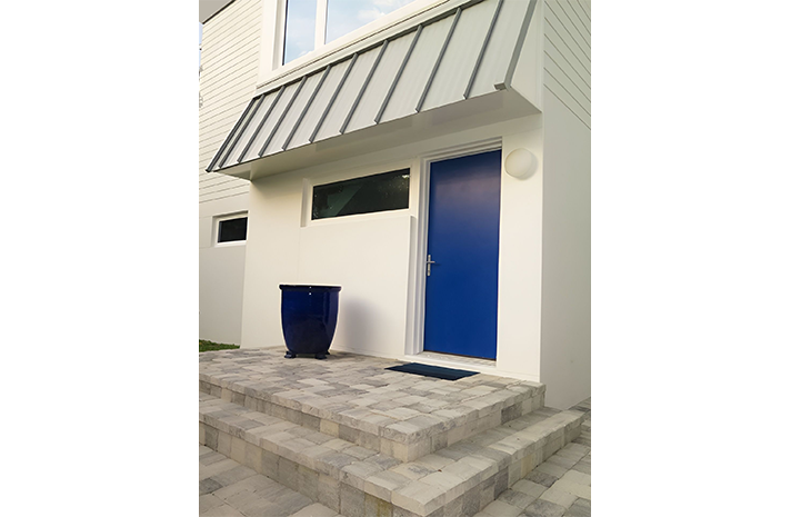 A blue door is on the front of a white house.