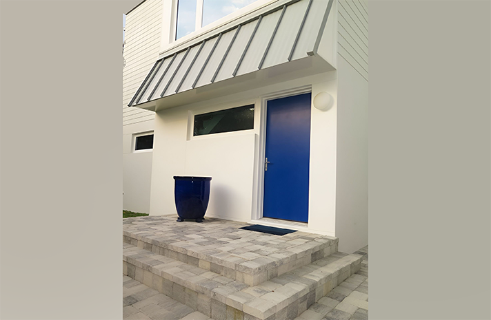 A white house with a blue door and steps