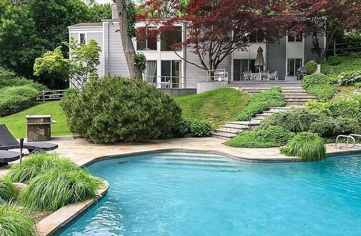 There is a large swimming pool in the backyard of a house.