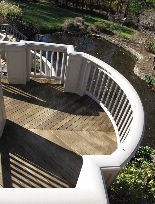 A wooden deck with a white railing overlooking a pond
