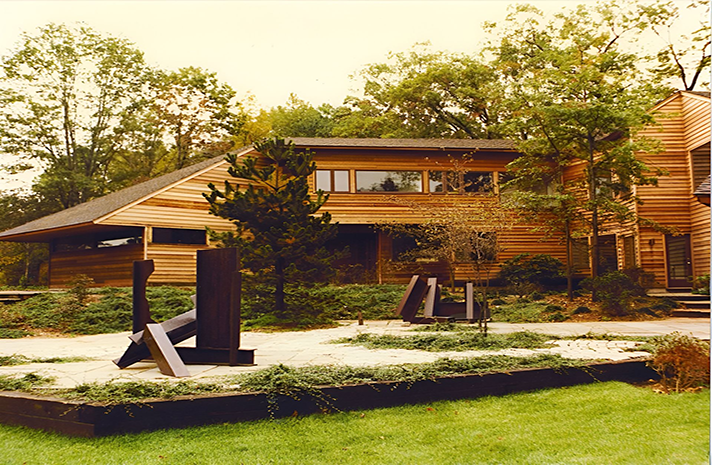 A large wooden house with a sculpture in front of it