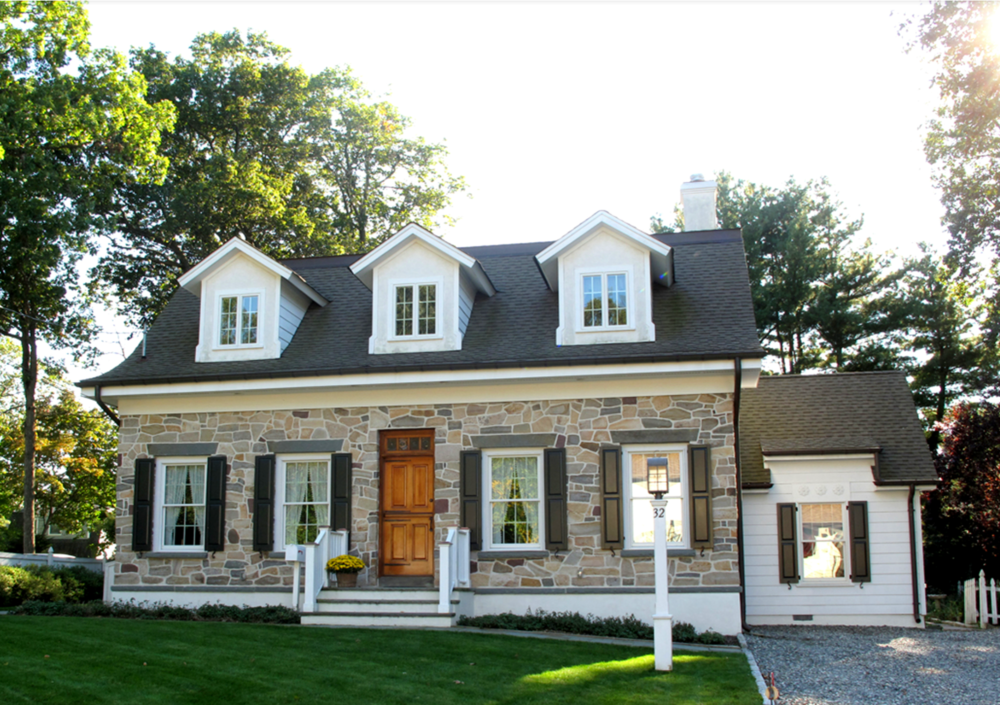 A stone house with white trim and black shutters