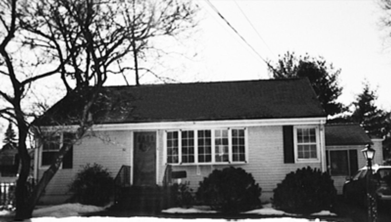 A black and white photo of a house with a black roof