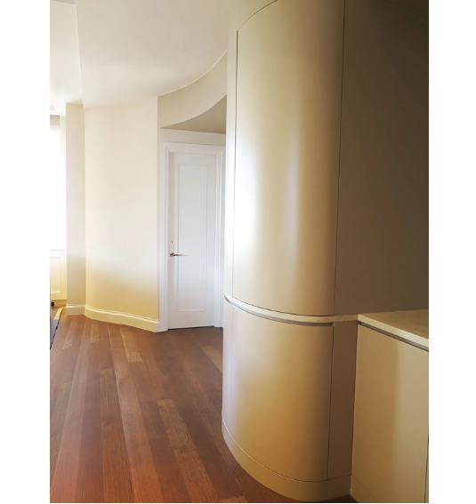 A hallway with a curved wall and a door