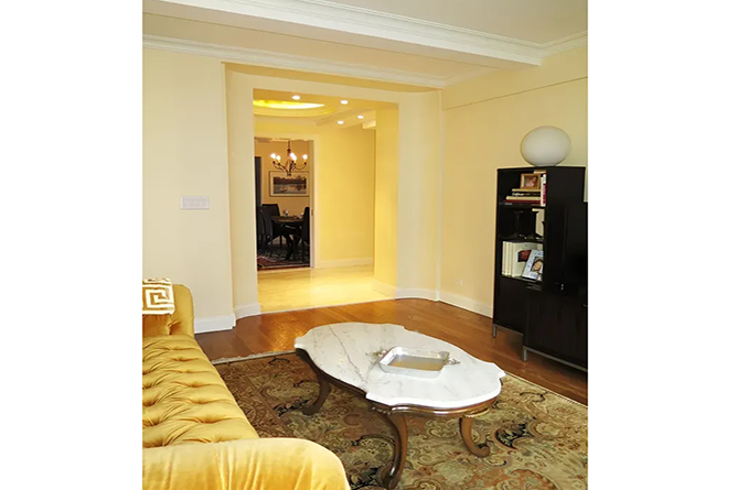 A living room with a yellow couch and a white coffee table