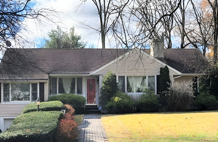 A white house with a black roof and a red door