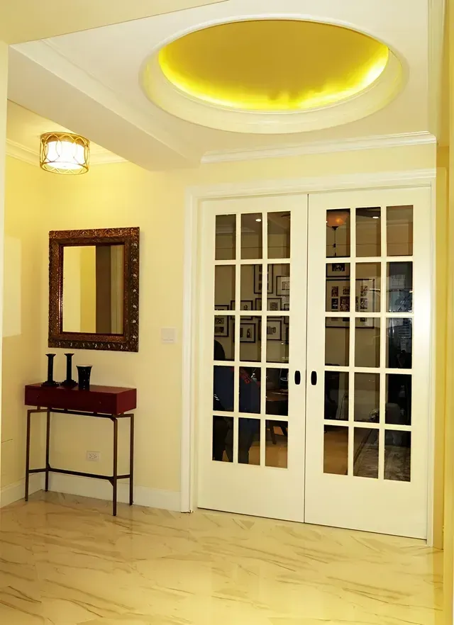 A hallway with french doors and a mirror on the wall