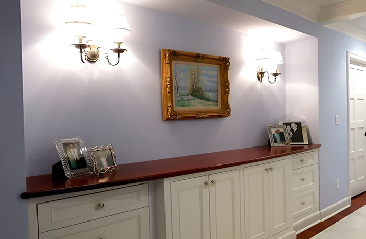 A hallway with white cabinets and a picture on the wall