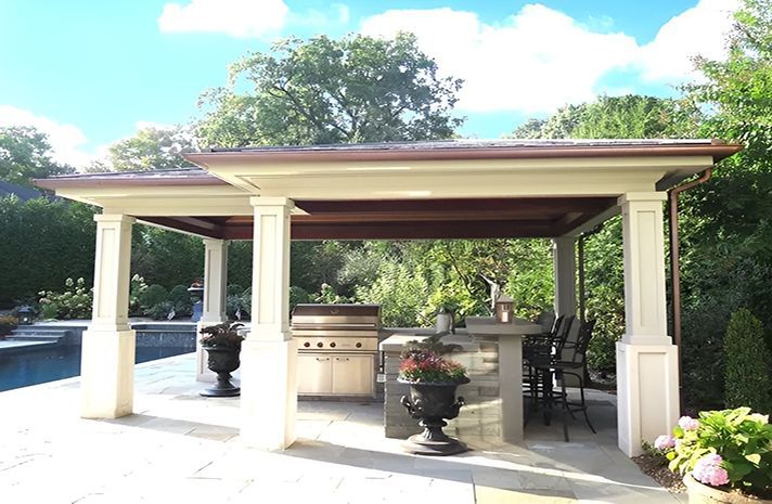 A pergola with a grill and a table underneath it