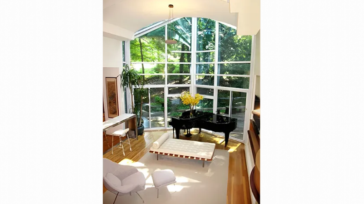 A living room with a piano and lots of windows